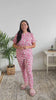 Women standing in a bedroom wearing cute pink bamboo pajamas with cute puppies on them. The Pajamas are a tee shirt top and jogger pant bottom. 