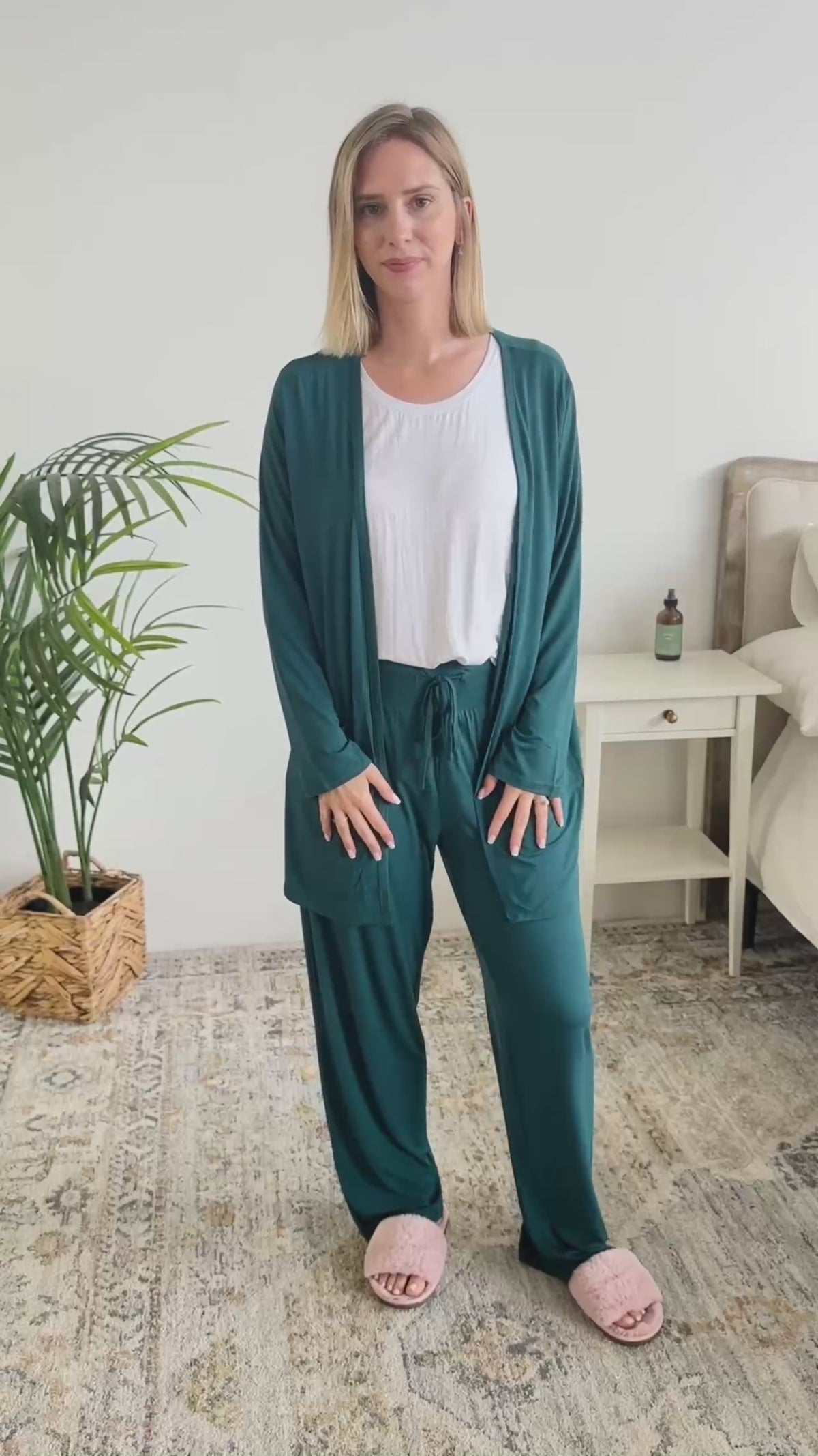 Women standing in a bedroom talking about the dark teal long bamboo cardigan. 