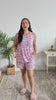 Women standing in a bedroom talking about her pajamas. She is wearing a tank and short bamboo set of pajamas with cute cats on them. 