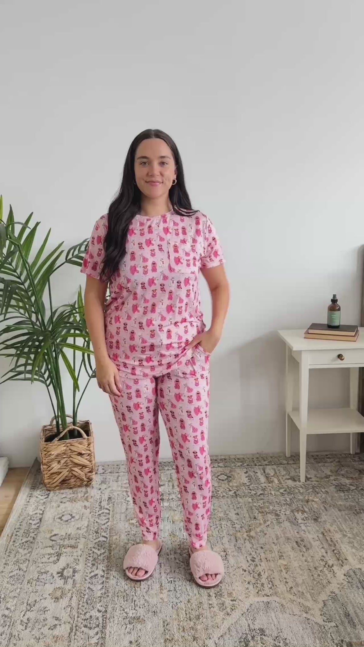 Women standing in bedroom showing her pajamas. The pajamas are pink with a tee and pant and cute dogs on them. 