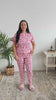 Women standing in bedroom showing her pajamas. The pajamas are pink with a tee and pant and cute dogs on them. 