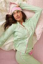 Pupcation Palms Vacay Mode Kiwi Stripe 3-Piece PJ Set PJ Salvage, model wearing green and pink striped pajamas on a bed.