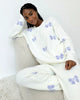 Model wearing Splendid Cloud-Soft Fuzzy Sweater Pajama Set, featuring soft fabric and purple butterfly pattern.
