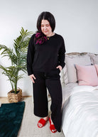 Model wearing Black Long Sleeve Raw Edge Straight Pant Cloud Lounge Set with red slippers in a cozy bedroom setting.