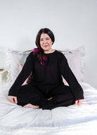 Black Long Sleeve Raw Edge Straight Pant Cloud Lounge Set worn by a woman sitting cross-legged on a bed.