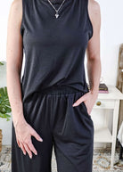 Woman wearing a sleepwear set with a black sleeveless top and pants in a home setting. With elastic waistband. 