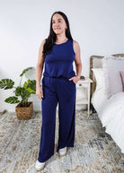 Woman wearing a sleepwear set with a navy sleeveless top and pants in a home setting. 
