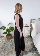 Woman wearing a sleepwear set with a black sleeveless top and pants in a home setting. 