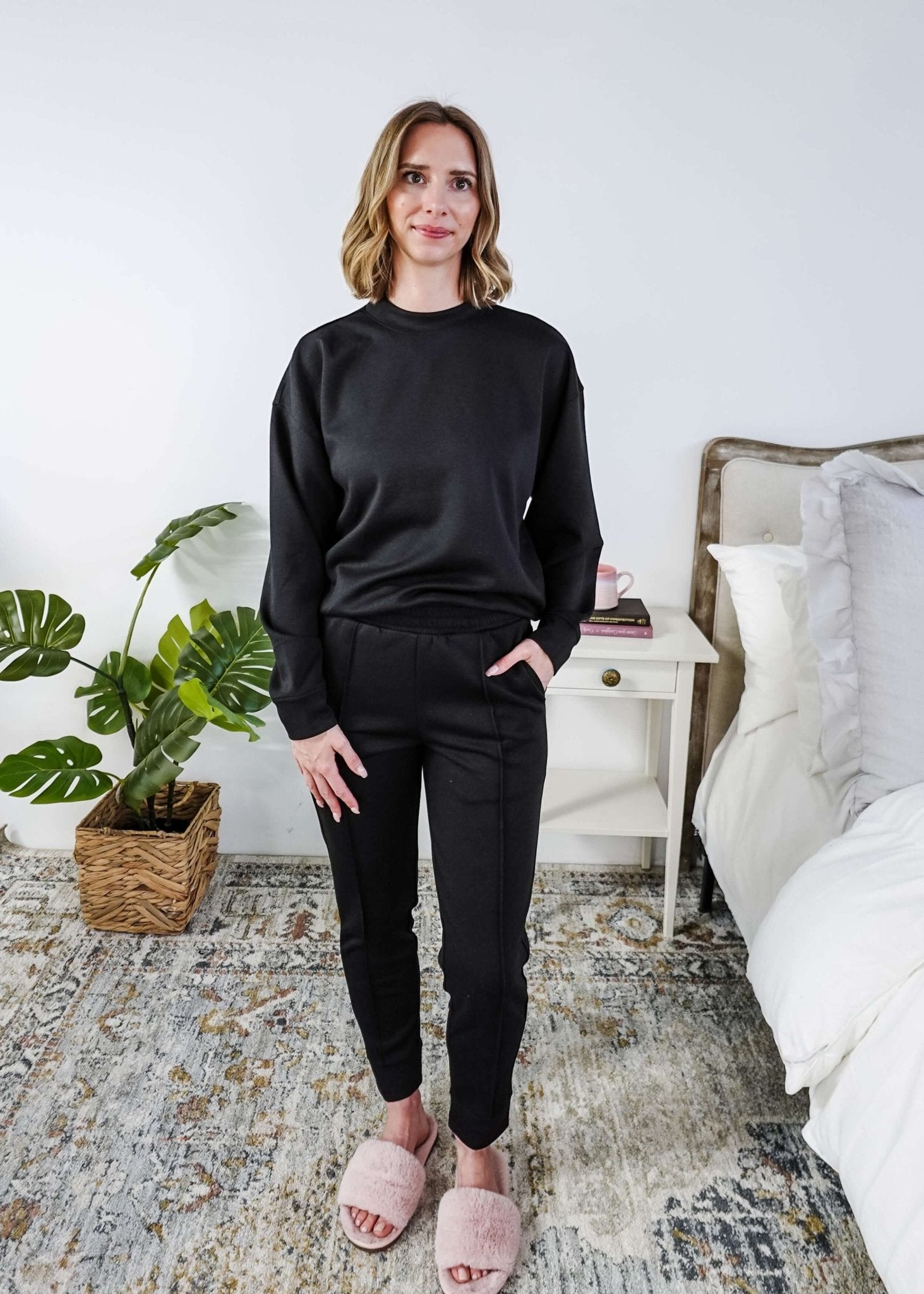 Woman wearing a black lounge outfit in a bedroom setting