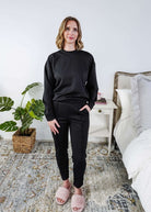 Woman wearing a black lounge outfit in a bedroom setting