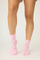 Pair of PJ Salvage Bright Pink Fuzzy Crew Socks with a whimsical all-over white bow print. Showing the plush texture and grip soles.