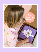 A woman in pajamas eagerly preparing to unbox The Dreamer's Club Seasonal Box - Spring Edition.