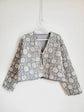 Floral print blue quilted jacket by French Toast Handmade. Hanging from a hanger on a light background