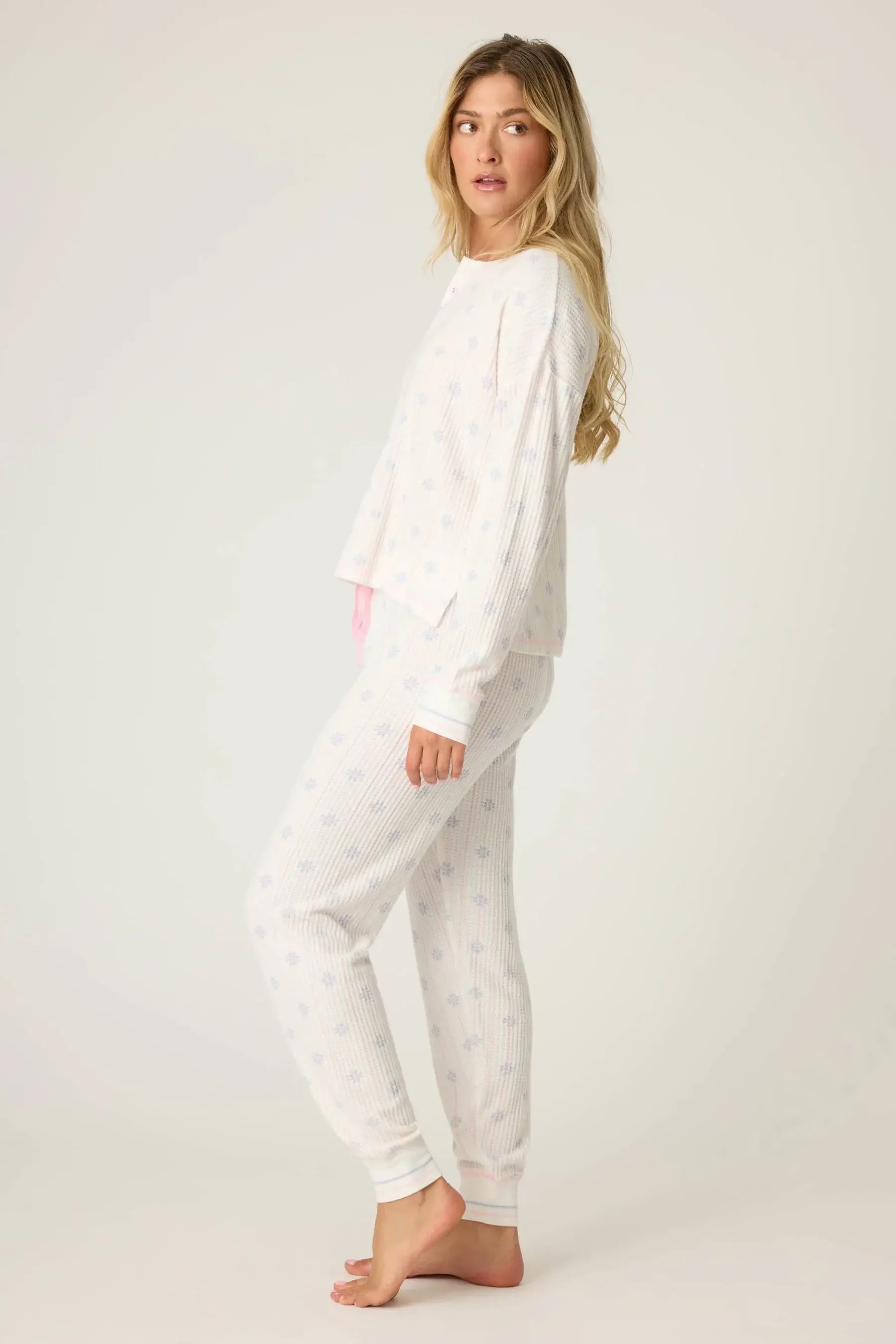 Woman wearing Snowflake Wishes Thermal PJ Set in ivory with snowflake pattern, featuring a cozy henley top and jogger pants.