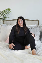plus size woman sitting wearing black lounge set with top and jogger in bamboo blend