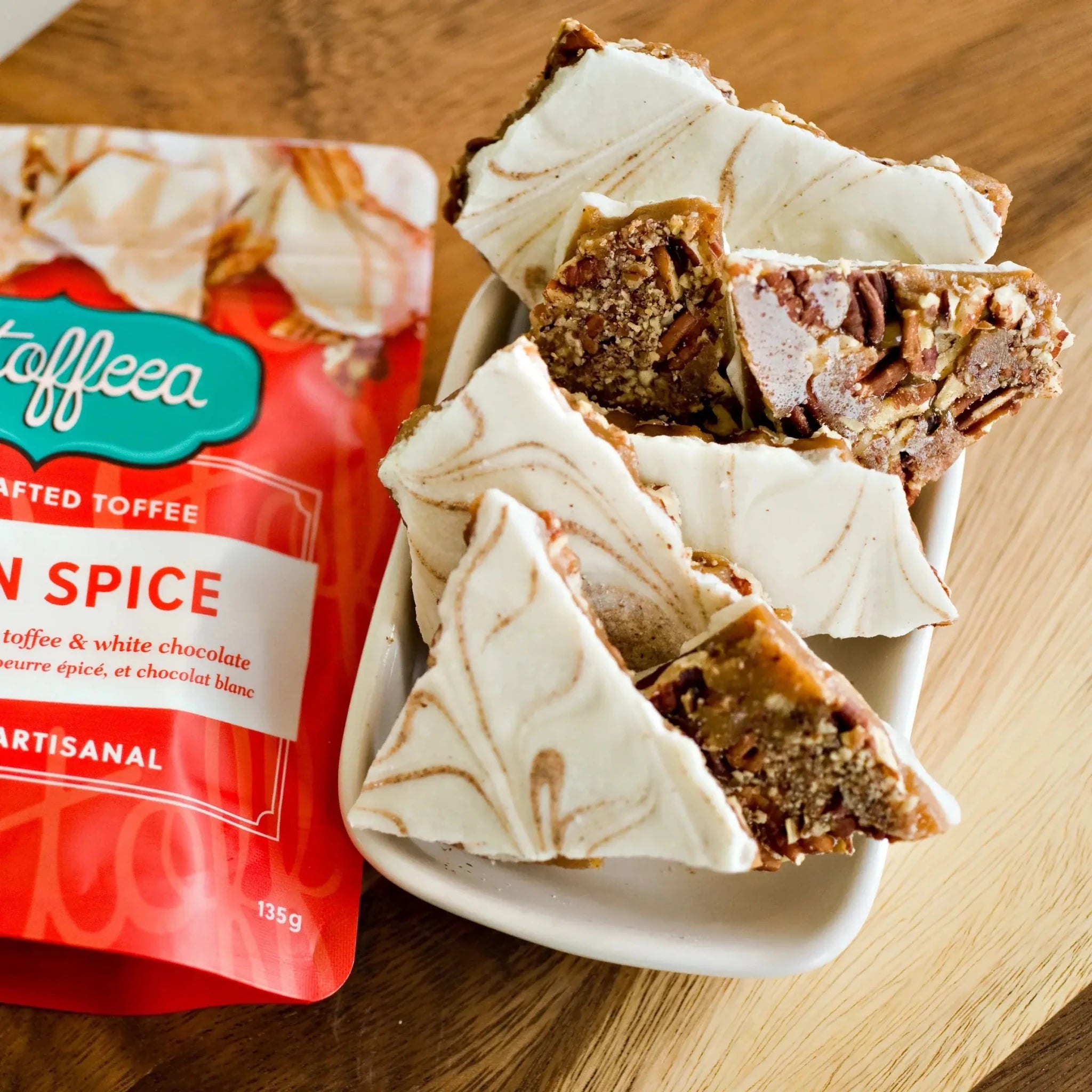 Utoffeea Canada Handcrafted Toffee with pumpkin spice flavor in a bowl next to its packaging.