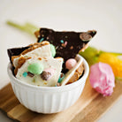 Utoffeea Canada Handcrafted Toffee pieces in a white bowl surrounded by flowers.