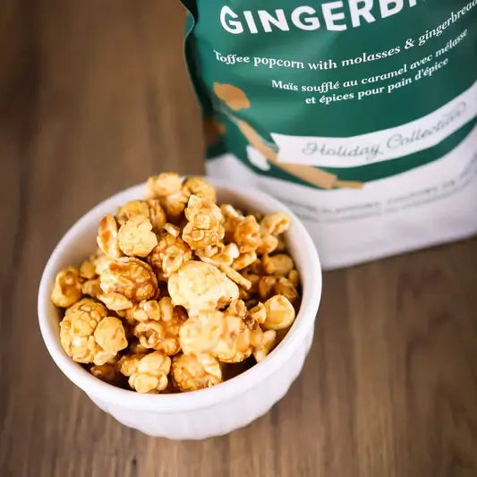 Gingerbread Toffee Popcorn in a white bowl beside Utoffeea Gourmet bag, perfect festive snack for the holidays.