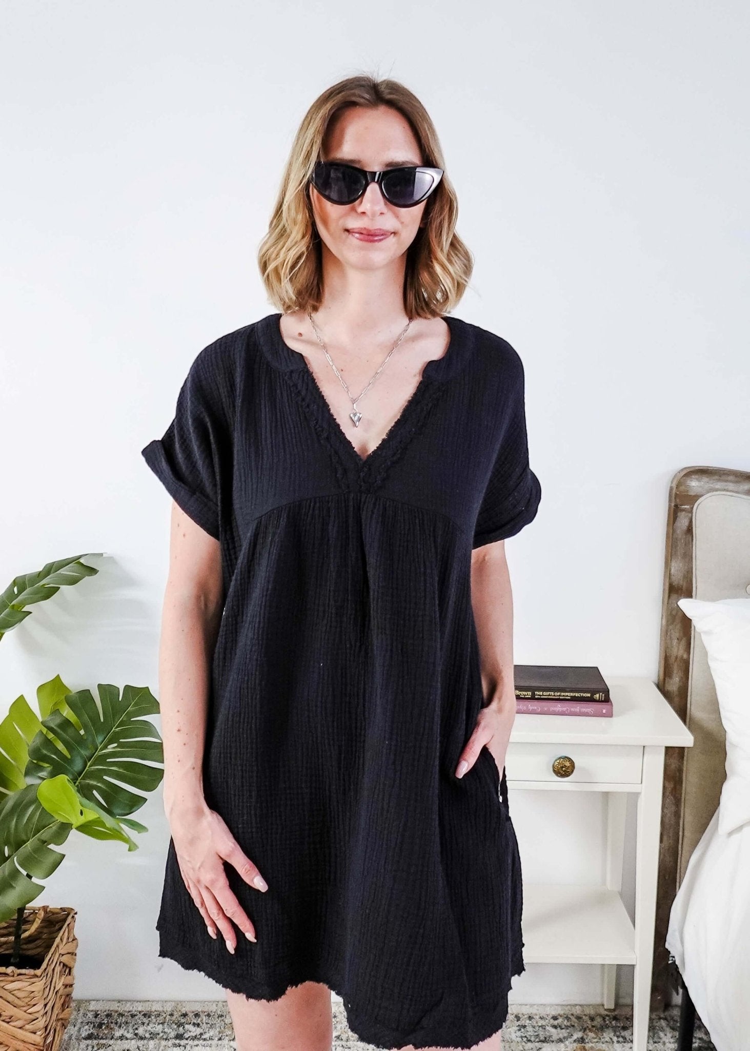 Woman wearing a black dress and sunglasses indoors with a plant and furniture in the background - Scarlett Ellie V-Neck Gauze Dress | Lightweight Summer Dress | Cloud Nine Pajamas
