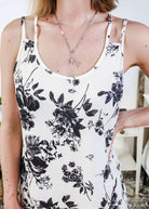 Woman wearing a black and white floral dress standing in a bedroom.