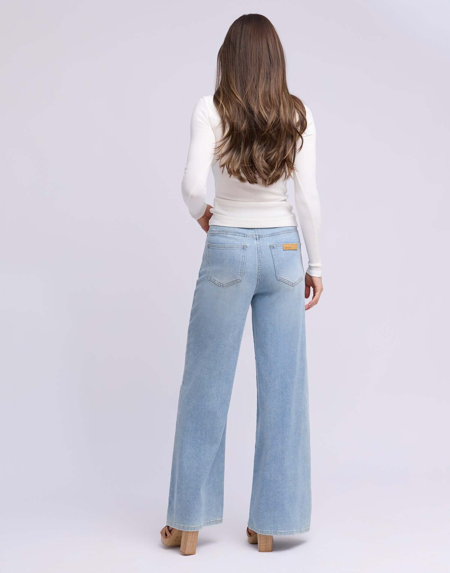 Woman wearing Yoga Jeans LILY Wide Leg Drawstring Jeans, view from the back showcasing the light blue denim style.