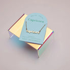 Zodiac Script Necklace in 14K Plated Gold displayed on a holographic stand with Capricorn card.