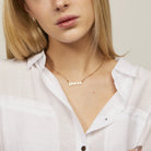 Zodiac Script Necklace in 14K Plated Gold featuring the Pisces astrological sign on a bright yellow display card.
